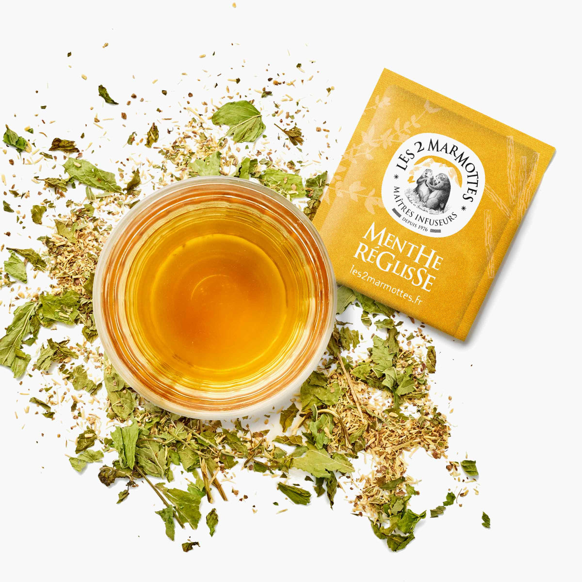 Tasse de tisane à la menthe et à la réglisse avec un sachet de tisane jaune les 2 marmottes